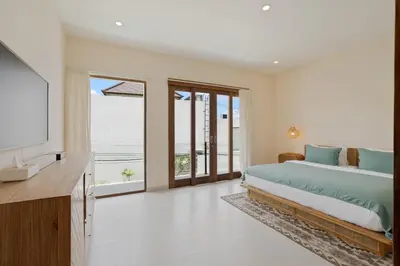 a bedroom with a bed and a tv and some windows at Roselle Villa by Betterplace in Canggu