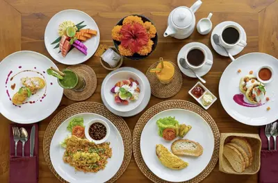 a wooden table with plates of food and cups of coffee at New Villa Lotus 2BR Private Pool Villas in Seminyak