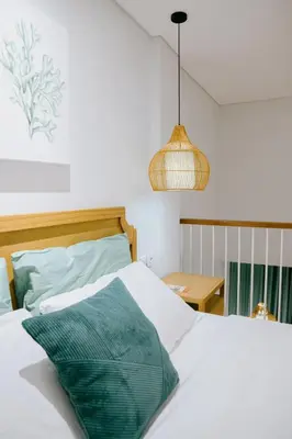 a bedroom with a white bed with a green pillow at Casa Amarta Canggu - Boutique Lofts & Detox SPA in Canggu
