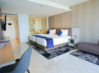a bedroom with a king sized bed and a desk at Platinum Hotel Jimbaran Beach Bali in Jimbaran