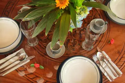 a wooden table with plates and a vase with a flower at Villa Yauda - Charming 3BR w/Private pool & Garden in Seminyak