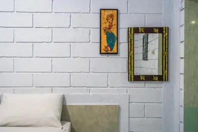 a white brick wall with two mirrors and a couch at Ammara Legian By Vilarisi - 8 Minute Walk To The Beach in Legian