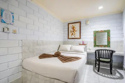 a bedroom with two beds and a chair at Ammara Legian By Vilarisi - 8 Minute Walk To The Beach in Legian