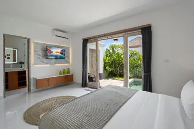 a white bedroom with a bed and a sliding glass door at Serenity Villa by Betterplace in Kerobokan