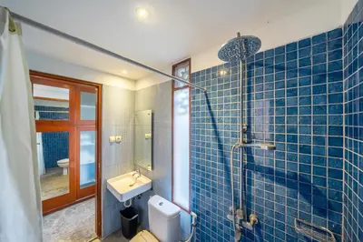 a blue tiled bathroom with a sink and a shower at Villa Arumanis in Canggu