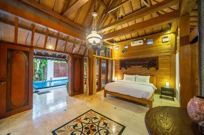 a bedroom with a bed in a room with wooden walls at Villa Arumanis in Canggu