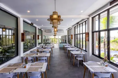 a row of tables and chairs in a restaurant with windows at Luxotic Private Villa and Resort in Nusa Dua