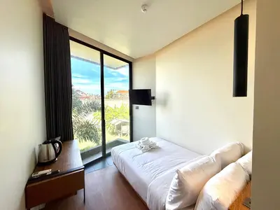 a bedroom with a bed and a large window at The Fields Hotel and Apartment in Seminyak