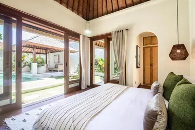 a bedroom with a large bed and a large window at Colonial-style 4BR Villa, 400m to Canggu Beach in Canggu