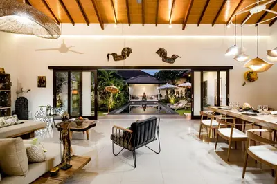 an open living room with a pool and tables and chairs at Villa Jami by BaliSuperHost in Seminyak