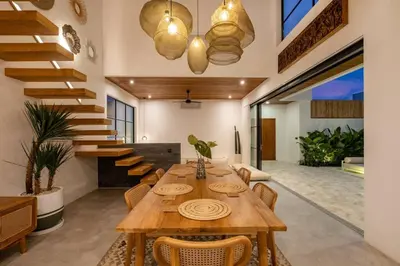 a dining room with a wooden table and stairs at Villa Solaris Umalas by Santi Management in Kerobokan