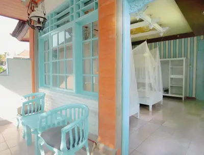 a porch with two chairs and a table and a crib at BS Home in Kuta