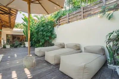 a patio with two white couches and an umbrella at Villa Marula at Bidadari in Seminyak