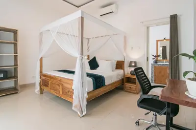 a bedroom with a canopy bed with a desk and a chair at Stylish Three Bedroom Villa Near Atlas Beach Club & Beach. in Canggu
