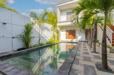 a swimming pool in front of a house with palm trees at Villa Rose 1 Sanur in Sanur