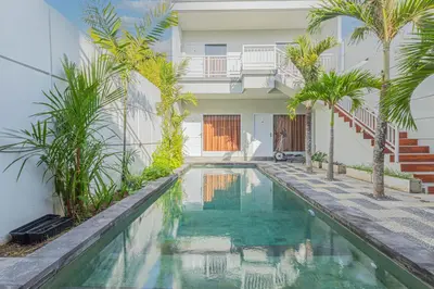 a swimming pool in front of a house with palm trees at Villa Rose 1 Sanur in Sanur