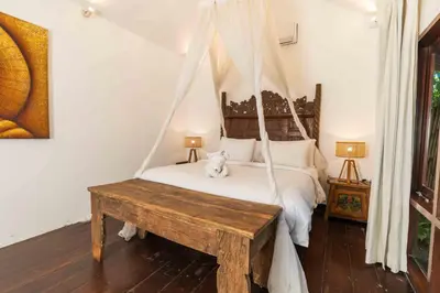 a bedroom with a hammock bed with a wooden table at The Gardens Seminyak in Seminyak