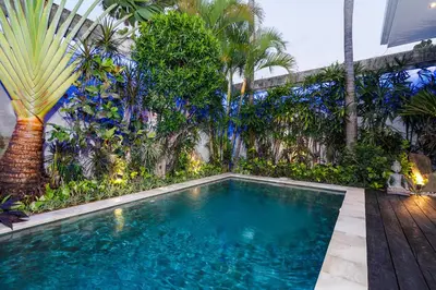 a swimming pool in a garden with palm trees at Villa Celine 2 chambres piscine Seminyak BALI in Seminyak