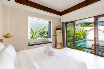 a bedroom with a white bed and a large window at J4 Villas Sanur in Sanur