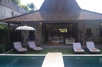 a backyard with a swimming pool and chairs and a house at Villa Joglo Oberoi Seminyak Beautiful 4BR Villa Prime Location in Seminyak