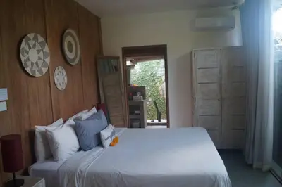 a bedroom with a large white bed and wooden walls at Villa Joglo Oberoi Seminyak Beautiful 4BR Villa Prime Location in Seminyak