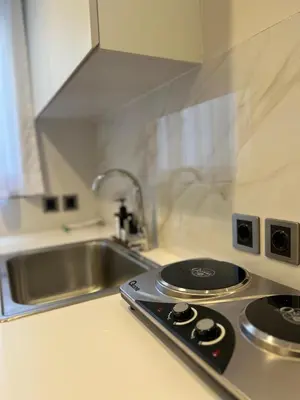 a kitchen counter with a stove and a sink at Charlie Guest House in Nusa Dua