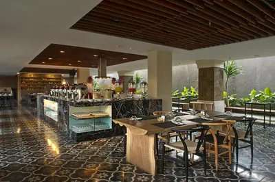 a restaurant with tables and chairs and a bar at Grand Zuri Kuta Bali in Kuta