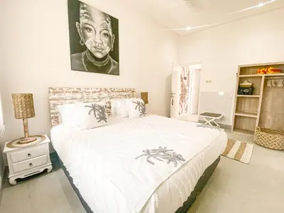 a bedroom with a large bed with a painting on the wall at Villa Coco Legian in Legian
