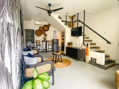 a living room with chairs and a tv and stairs at Villa Coco Legian in Legian