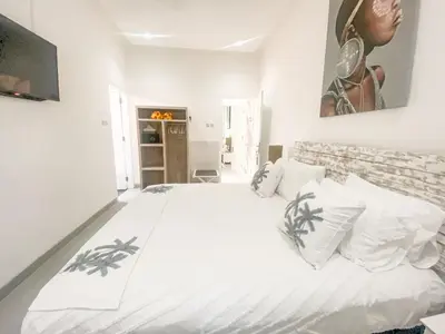 a white bedroom with a large bed with white pillows at Villa Coco Legian in Legian