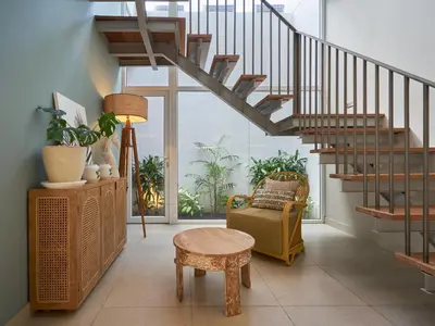 a living room with a staircase and a chair at Luna Ola Villa Berawa in Canggu