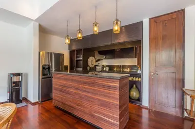 a kitchen with a large wooden bar in a room at Eshara 1 our Tropical & luxury 3BR Villa 450m from beach in Seminyak