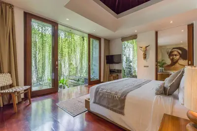 a bedroom with a large bed and large windows at Eshara 1 our Tropical & luxury 3BR Villa 450m from beach in Seminyak