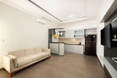 a living room with a couch and a kitchen at Jineswari Kuta by Kamara in Kuta