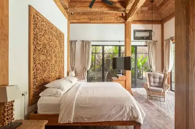 a bedroom with a large bed and a chair at Villa Lio - Tropical Escape in Canggu in Canggu