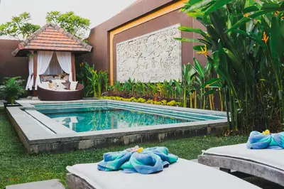 a resort with a swimming pool with towels on beds at Villa Lapiz in Seminyak