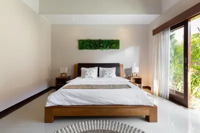 a bedroom with a large bed and a large window at Villa Lapiz in Seminyak