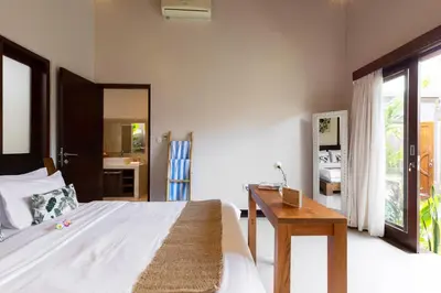 a bedroom with a bed and a desk and a mirror at Villa Lapiz in Seminyak