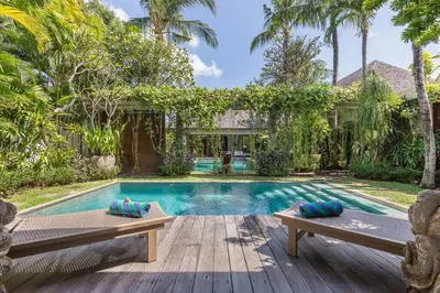 a swimming pool with two benches in front of a house at Eshara 123 in Oberoi our 8 BR Villa with 3 Pool close to Beach in Seminyak