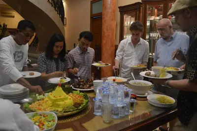 a group of people standing around a table eating food at Guildwood Villa Bali in Sanur