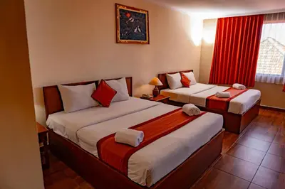 a hotel room with two beds and a window at Puri Dibia Kuta Hotel & Apartment in Kuta