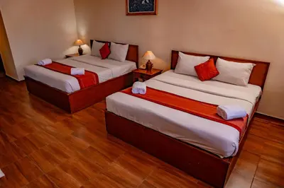 two beds in a room with wooden floors at Puri Dibia Kuta Hotel & Apartment in Kuta