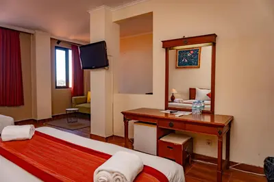 a hotel room with a desk and a mirror at Puri Dibia Kuta Hotel & Apartment in Kuta