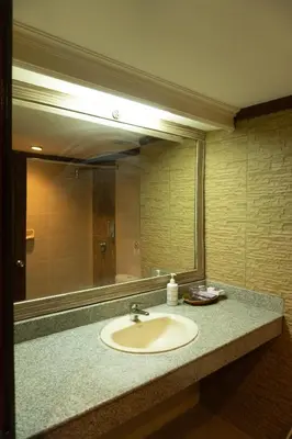 a bathroom with a sink and a large mirror at Puri Dibia Kuta Hotel & Apartment in Kuta