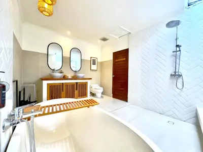 a bathroom with a tub and a sink and mirror at An Amazing 6BDR Private Family Villa with Pool in Tanah Lot