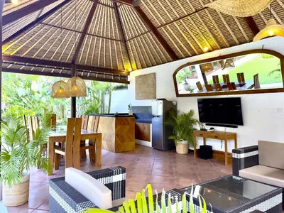 an outdoor patio with an umbrella and a television at An Amazing 6BDR Private Family Villa with Pool in Tanah Lot