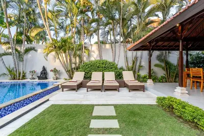 a patio with lounge chairs and a swimming pool at Viona 3 Villa - 3 BDR villa, walk to the beach in Seminyak