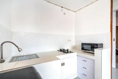 a white kitchen with a sink and a microwave at Lumturi House - Centrally Located in Seminyak