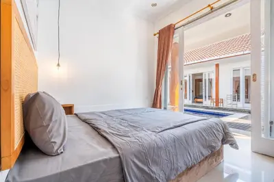 a bedroom with a bed and a large window at Lumturi House - Centrally Located in Seminyak