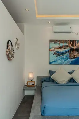 a bedroom with a blue bed and a painting on the wall at Villa Cempaka Ungu - Tranquil & Chic Pool 4-Bedroom Villa In The Heart Of Seminyak in Seminyak